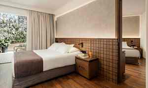 Hotellrum med dubbelsäng, nattbord och garderob. (AI-genererad text)