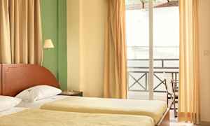 Ett hotellrum med två enkelsängar, gardiner och en balkong. (AI-genererad text)