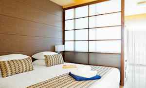 Ett hotellrum med en stor säng, träpaneler och en delvis transparent skjutdörr. (AI-genererad text)