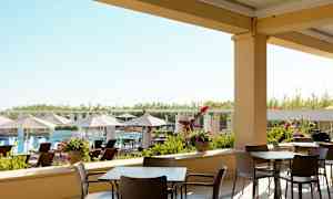 Uteservering med stolar och bord, med utsikt mot en pool och solstolar. (AI-genererad text)