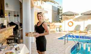 En person håller i en korg med bröd nära ett serveringsområde vid en pool med solsängar. (AI-genererad text)