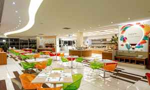 En matsal med färgglada stolar och dukade bord, samt en buffé i bakgrunden. (AI-genererad text)