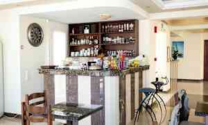 En kafé- eller barområde med en marmorbardisk, stolar och hyllor fyllda med glas och porslin. (AI-genererad text)