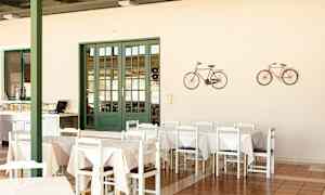 En matplats med bord och stolar, en grön dörr och dekorationer av cyklar på väggen. (AI-genererad text)