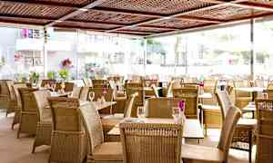 Restaurang med rottingmöbler och blommor på borden. (AI-genererad text)