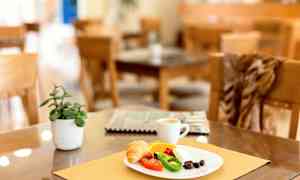 En tallrik serverad med frukost inklusive croissant, grönsaker och kaffe på ett bord med dekorationer. (AI-genererad text)