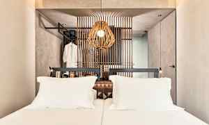 En hotellrum med en dubbelsäng och en dekorativ träpanel bakom sängen. (AI-genererad text)