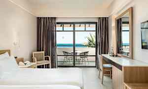 Hotellrum med säng, skrivbord och balkong med havsutsikt. (AI-genererad text)