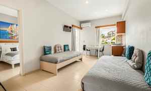 Ett hotellrum med två enkelsängar, ett bord och stolar, samt utsikt genom fönstret. (AI-genererad text)