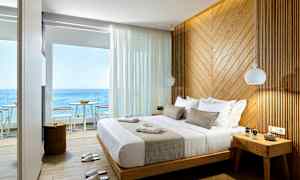 Ett hotellrum med havsutsikt, en stor säng och en vägg av träpanel. (AI-genererad text)