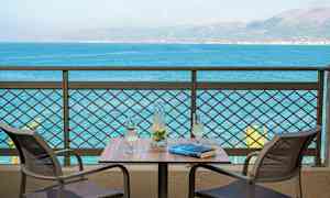 Två stolar vid ett bord med en karaff och två glas, med utsikt över havet. (AI-genererad text)