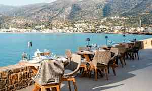 Uteservering vid havet med utsikt över bergen och en stad. (AI-genererad text)