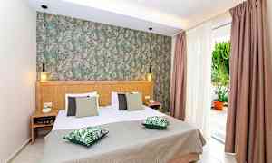 Sovrum med dubbelsäng, gröna kuddar och dekorerad vägg. (AI-genererad text)