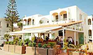 Vit byggnad med utomhusbar och sittmöbler. (AI-genererad text)