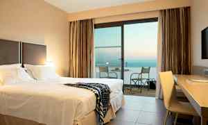 Hotellrum med dubbelsäng och balkong med havsutsikt. (AI-genererad text)