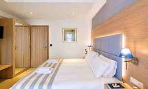 Ett hotellrum med en dubbelsäng, trädetaljer, blå lampor och ett spegelskåp. (AI-genererad text)