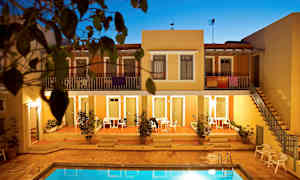 Lägenhetskomplex med en pool i förgrunden, omgiven av terrakottafärgade byggnader och grönska. (AI-genererad text)