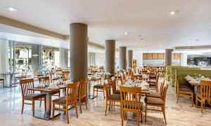 En ljus restaurang med trästolar och dukade bord. (AI-genererad text)