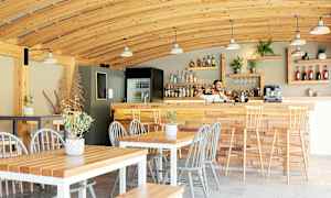 En kaféteria med träinredning, bord, stolar och en bardisk. (AI-genererad text)