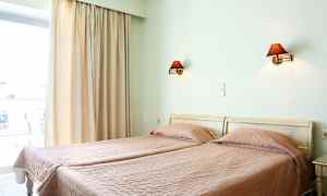 Två enkelsängar med rosa täcken i ett rum med en fönsteröppning och vägglampor. (AI-genererad text)