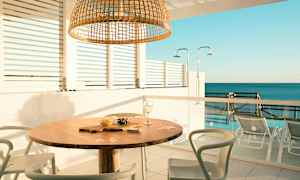 Utomhusområde med ett bord och stolar, havsutsikt i bakgrunden. (AI-genererad text)