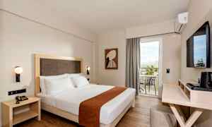 Hotellrum med en dubbelsäng, vägghängda lampor, och en balkong med utsikt. (AI-genererad text)