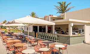Utomhusrestaurang med bar och sittplatser under parasoll. (AI-genererad text)