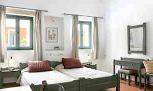 Bild av ett ljust sovrum med två enkelsängar, fönster med ljusinsläpp och möbler i trä. (AI-genererad text)