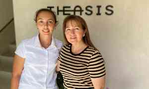 Två personer står framför en vägg med en logotyp. (AI-genererad text)