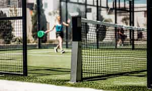 Padelbana med nät och spelare i bakgrunden. (AI-genererad text)