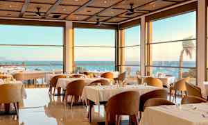 En elegant restaurang inomhus med stora fönster och havsutsikt. (AI-genererad text)