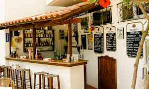 En liten utomhusbar med trästolar, dryckesflaskor på hyllorna och menyer på väggen. (AI-genererad text)