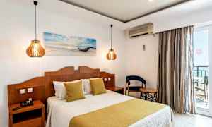 Ett hotellrum med en dubbelsäng, två nattduksbord med lampor och en stol bredvid ett bord. (AI-genererad text)