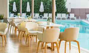 Uteservering vid pool med stolar och bord. (AI-genererad text)