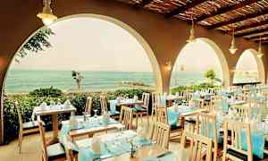 Restaurang med dukade bord och utsikt över havet genom valv. (AI-genererad text)