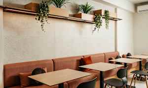 Ett modernt caféområde med röda soffor och träbord, dekorerat med växtlådor hängande ovanför. (AI-genererad text)