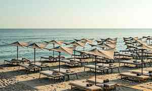 Strand med solstolar och parasoller vid havet. (AI-genererad text)