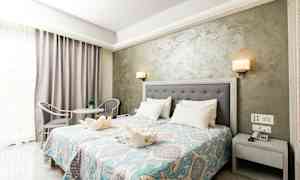 Ett hotellrum med dubbelsäng, nattduksbord, dekorativt överkast och sittgrupp. (AI-genererad text)