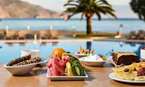 En frukost serveras vid ett bord nära en pool, med utsikt mot havet och palmträd. (AI-genererad text)