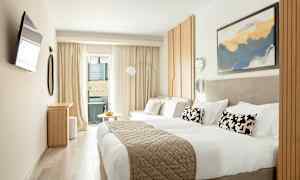 Ett modernt hotellrum med en dubbelsäng, ljusa möbler och dekorationer samt en liten sittgrupp nära ett fönster. (AI-genererad text)