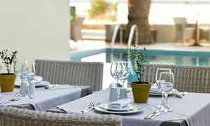 Ett dukat bord med vita tallrikar och glas, placerat intill en pool. (AI-genererad text)