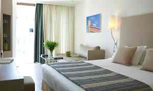 Ett modernt hotellrum med en stor säng, skrivbord och en bekväm sittplats i ljusa färger. (AI-genererad text)