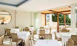 Restaurang med matbord och stolar, utsikt mot en terrass. (AI-genererad text)