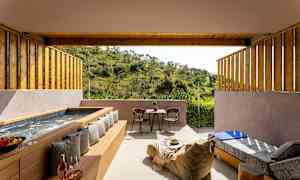 En uteplats med badkar, sittmöbler och en utsikt över grön natur. (AI-genererad text)