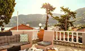 En terrass med soffgrupp och utsikt över tak och berg. (AI-genererad text)