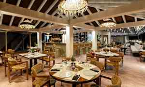 Restaurang med dukade bord, stolar och bar i bakgrunden. (AI-genererad text)