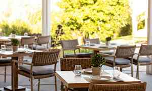 Ett luftigt område med bord och stolar, dekorerade med små växter och serveringsupplägg. (AI-genererad text)