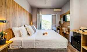 Hotellrum med en dubbelsäng, utsmyckat med träpaneler och en balkong med utsikt. (AI-genererad text)