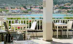 Utomhus terrass med bord och stolar, med havsutsikt i bakgrunden. (AI-genererad text)