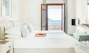 Ett hotellrum med en dubbelsäng, inrett i ljusa färger, och en altandörr som leder ut till en balkong med havsutsikt. (AI-genererad text)